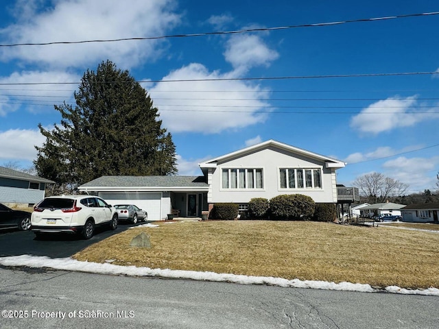 tri-level home with a garage, a front lawn, aphalt driveway, and stucco siding