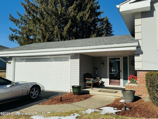 view of exterior entry with a garage, driveway, a porch, and roof with shingles