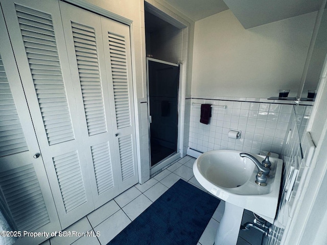 full bath featuring a wainscoted wall, a closet, a shower stall, and tile patterned floors