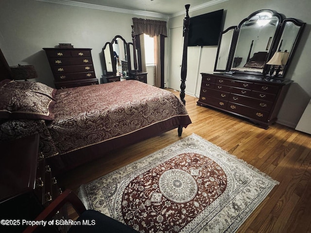 bedroom with ornamental molding and wood finished floors