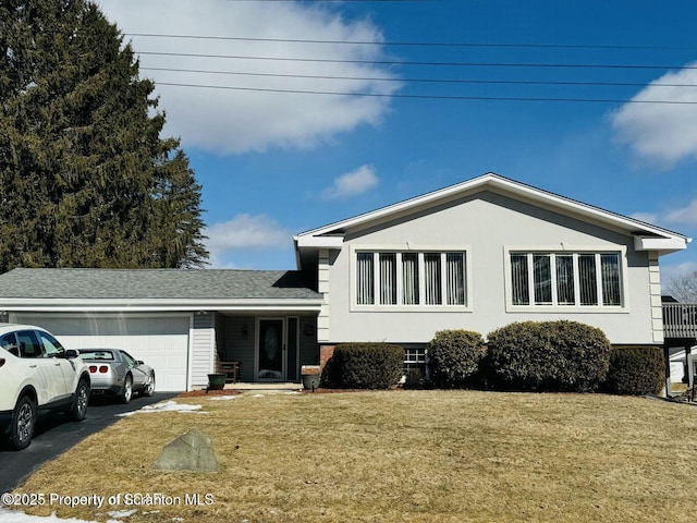 tri-level home with a garage, a front yard, driveway, and stucco siding