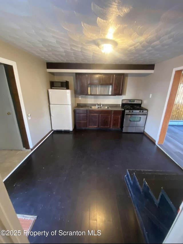 kitchen with dark brown cabinetry, sink, dark wood-type flooring, and stainless steel appliances