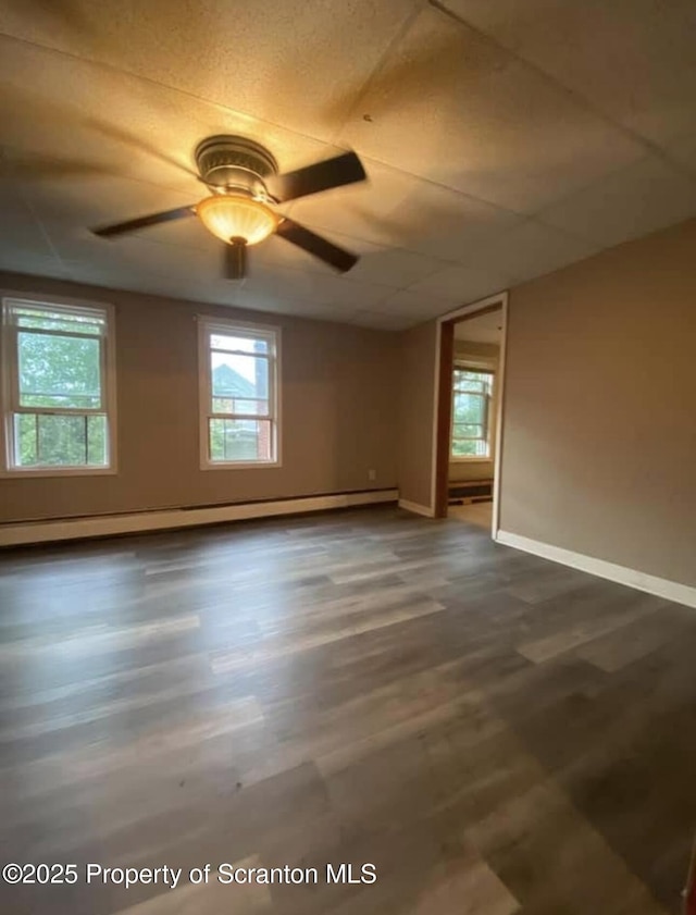 empty room with ceiling fan, a baseboard radiator, and dark hardwood / wood-style floors