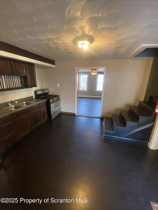 kitchen with ceiling fan, sink, gas stove, and dark brown cabinets