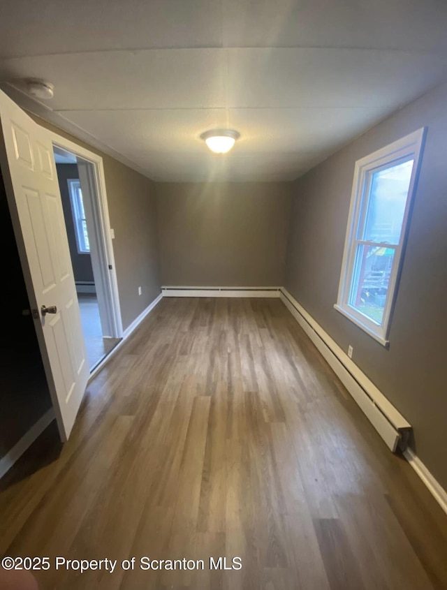 unfurnished room with hardwood / wood-style floors and a baseboard radiator