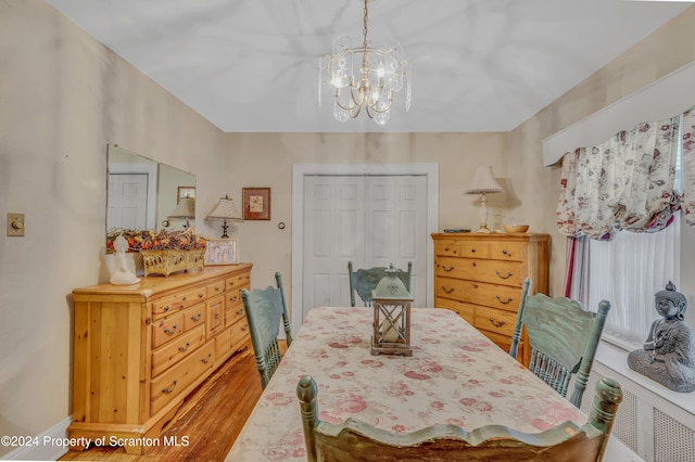 dining space with hardwood / wood-style flooring and a chandelier