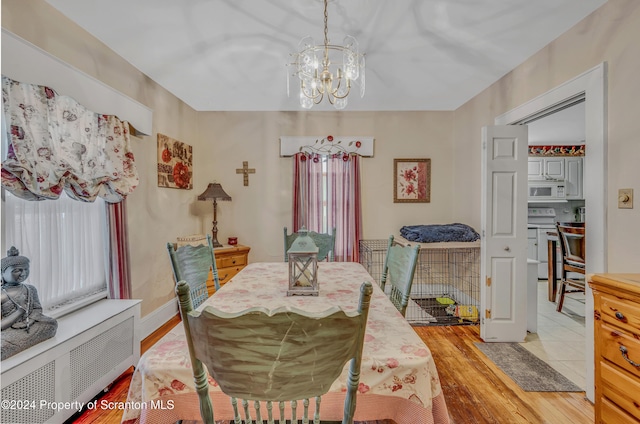 dining area featuring radiator heating unit, light hardwood / wood-style floors, an inviting chandelier, and a wealth of natural light