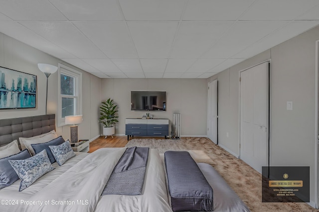 bedroom with a paneled ceiling and light hardwood / wood-style flooring