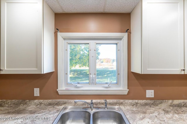 kitchen with a paneled ceiling, sink, and white cabinets