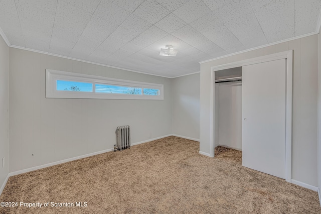 unfurnished bedroom featuring radiator, crown molding, a closet, and light carpet