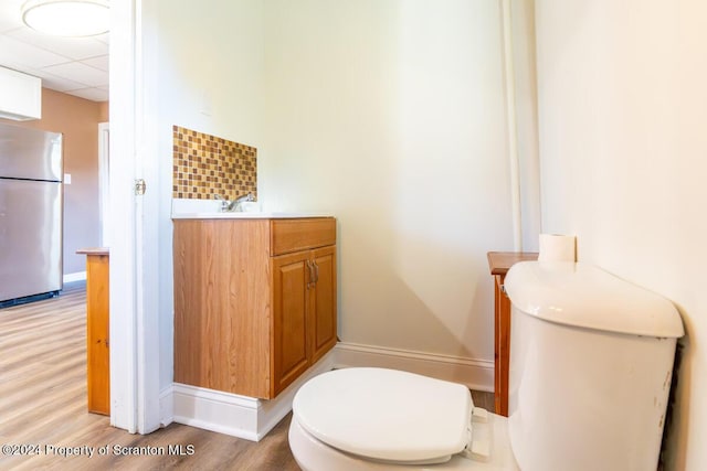 bathroom featuring a drop ceiling, toilet, wood-type flooring, and vanity