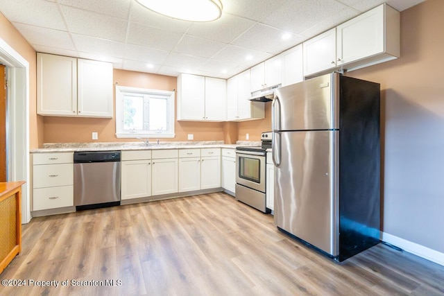 kitchen with light wood-type flooring, a paneled ceiling, stainless steel appliances, sink, and white cabinetry