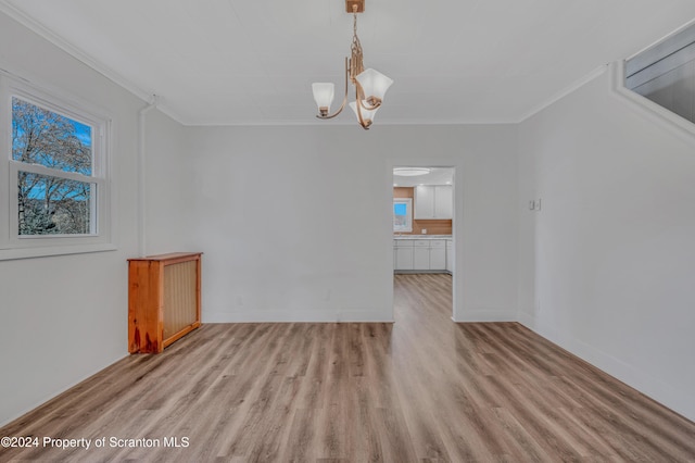 unfurnished dining area with light wood-type flooring, a notable chandelier, and ornamental molding