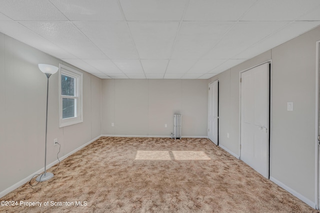 carpeted empty room featuring a drop ceiling