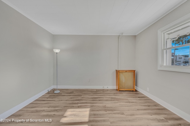 empty room with light hardwood / wood-style floors and ornamental molding