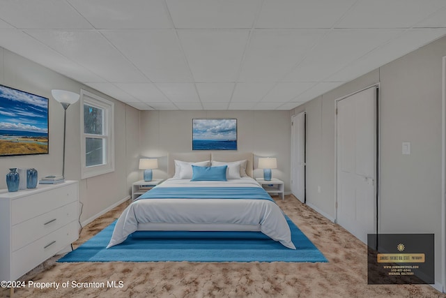 bedroom with light carpet and a drop ceiling