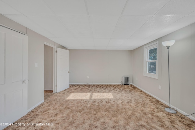 empty room with carpet, a paneled ceiling, and radiator heating unit