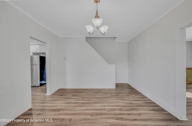 unfurnished dining area with ornamental molding, light wood-type flooring, and a notable chandelier