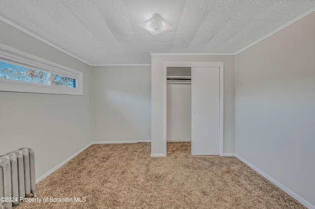 unfurnished bedroom featuring a closet, light colored carpet, radiator, and crown molding