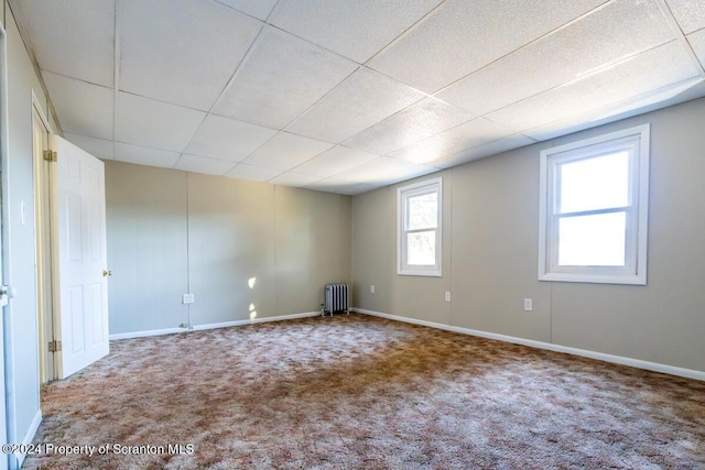 unfurnished room with carpet flooring, a paneled ceiling, and radiator