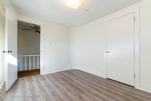 spare room with light hardwood / wood-style floors, a drop ceiling, and ceiling fan