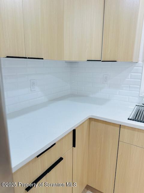 kitchen with light brown cabinetry and decorative backsplash