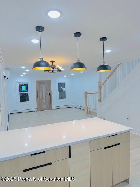 kitchen featuring baseboard heating, decorative light fixtures, a wall mounted AC, and light brown cabinetry