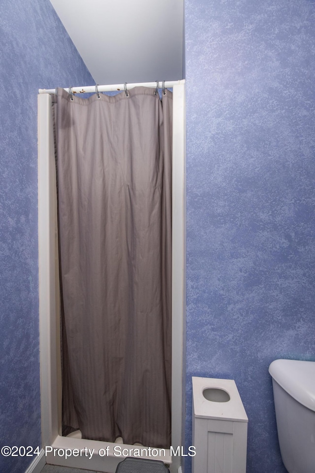 bathroom featuring a shower with curtain and toilet