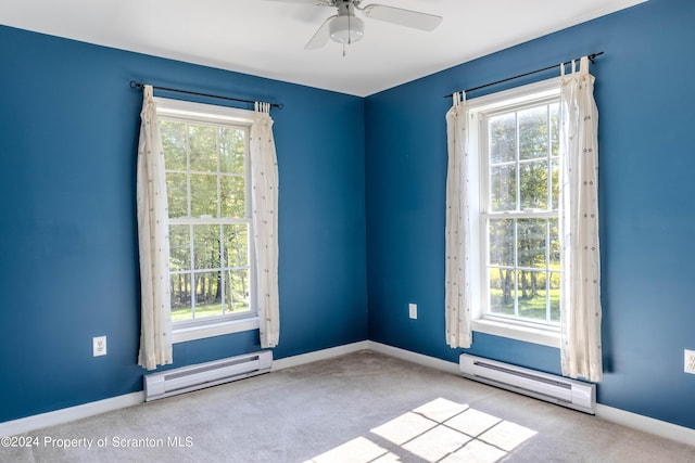 empty room featuring a healthy amount of sunlight, ceiling fan, and a baseboard heating unit