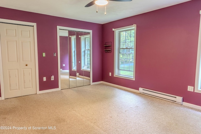 unfurnished bedroom with baseboard heating, multiple closets, and ceiling fan