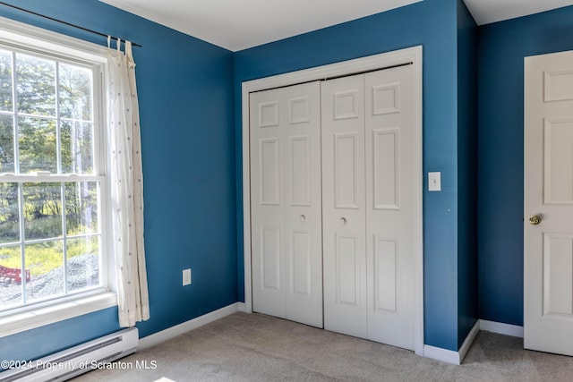 unfurnished bedroom with light carpet, a closet, and a baseboard radiator