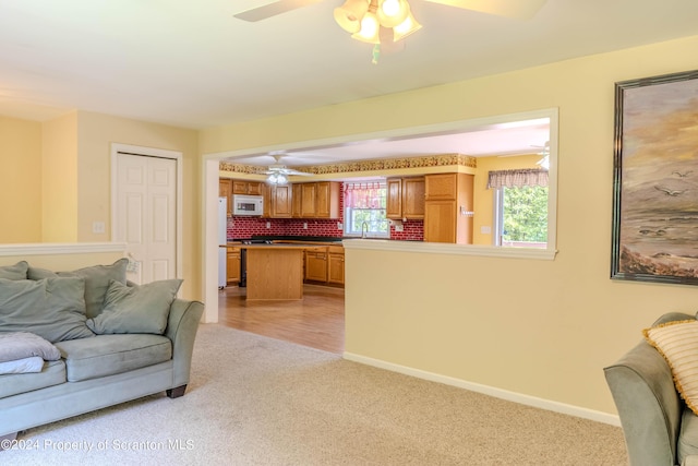 carpeted living room with ceiling fan and sink