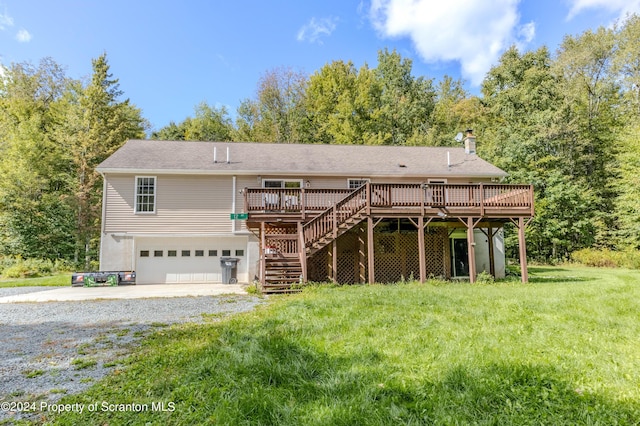 rear view of house featuring a garage, a deck, and a yard