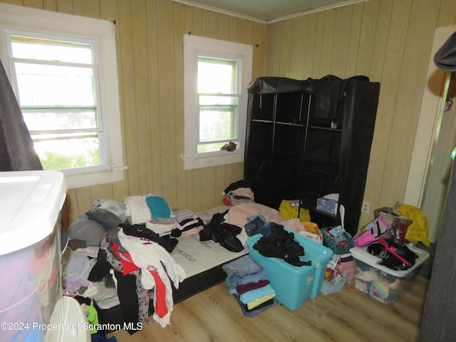 bedroom featuring wood walls, hardwood / wood-style floors, and ornamental molding