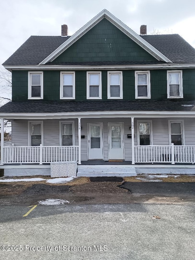 view of front of house with a porch, a chimney, and a shingled roof