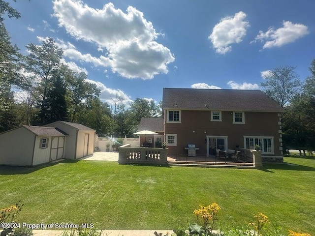 rear view of property with a shed, a yard, and a deck