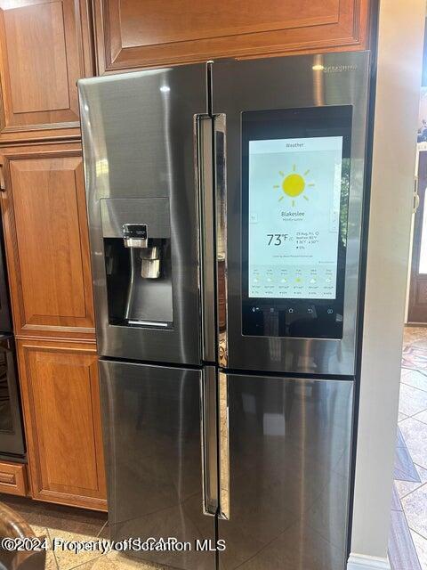 interior details featuring stainless steel fridge with ice dispenser and black oven