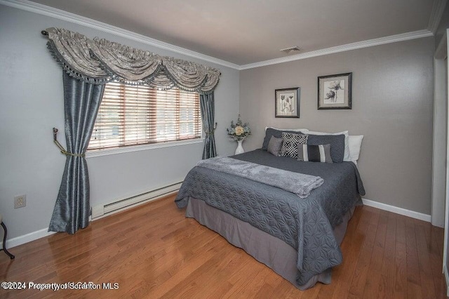 bedroom with ornamental molding, a baseboard heating unit, and hardwood / wood-style floors