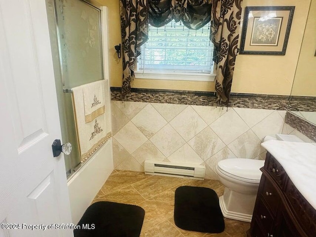 full bathroom with vanity, shower / bath combination with glass door, tile patterned floors, tile walls, and a baseboard radiator