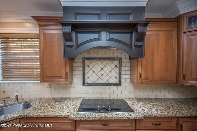 kitchen featuring backsplash, light stone counters, ornamental molding, black electric cooktop, and sink