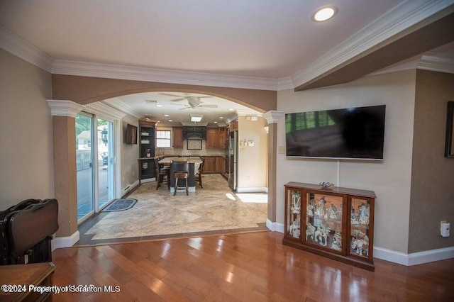 living room featuring ceiling fan, ornamental molding, and light hardwood / wood-style flooring