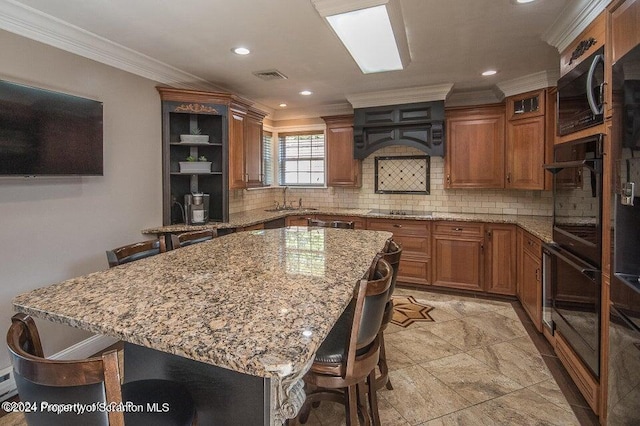 kitchen with black appliances, a kitchen breakfast bar, a kitchen island, and sink