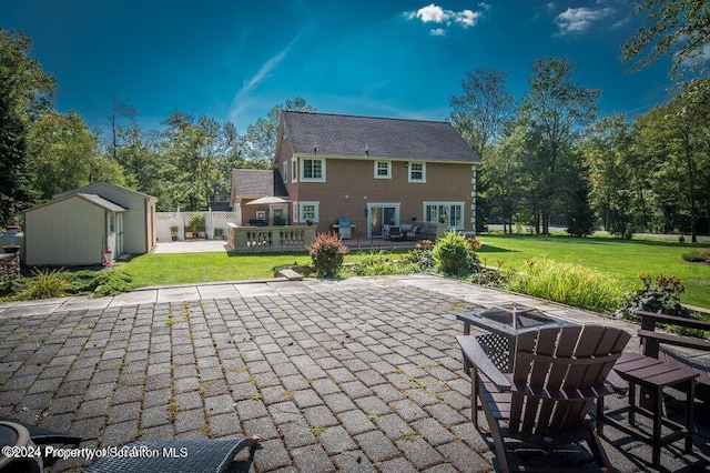 back of property featuring a fire pit, a storage unit, a yard, and a patio