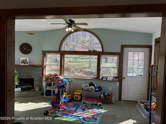 recreation room featuring a ceiling fan, carpet, visible vents, and a brick fireplace