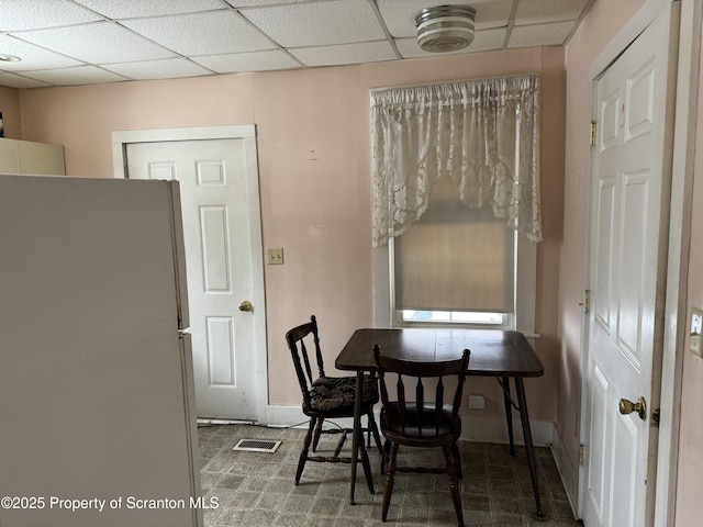 dining space featuring a drop ceiling, visible vents, and baseboards