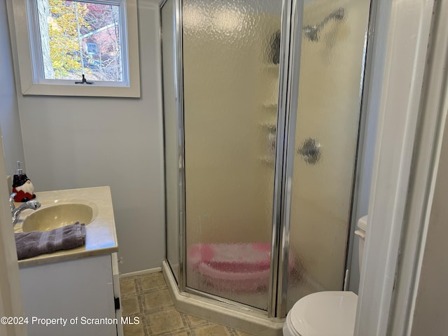 full bath with toilet, a shower stall, vanity, and baseboards