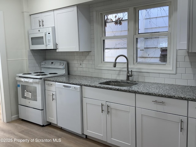 kitchen featuring sink, white cabinetry, stone counters, white appliances, and light hardwood / wood-style floors