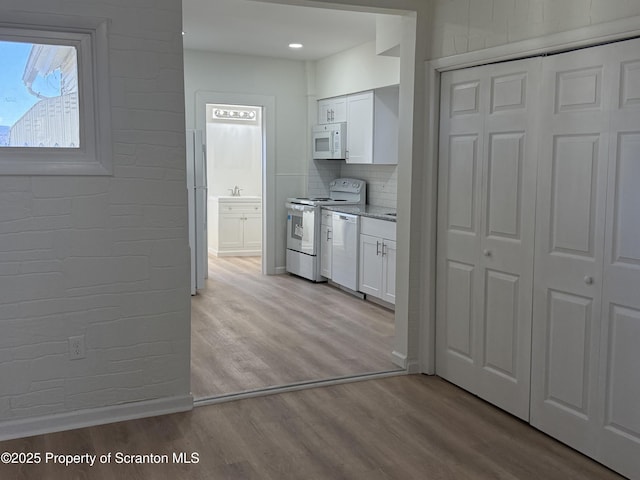 kitchen featuring white cabinetry, light stone counters, white appliances, light hardwood / wood-style floors, and backsplash