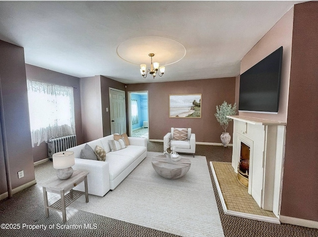 living room with a brick fireplace, radiator, and a notable chandelier