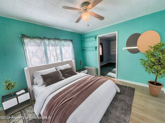 bedroom with hardwood / wood-style flooring, ornamental molding, radiator heating unit, and ceiling fan